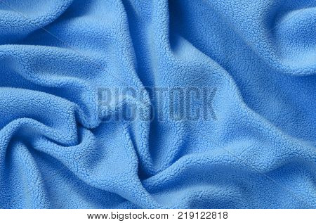 The blanket of furry blue fleece fabric. A background of light blue soft plush fleece material with a lot of relief folds