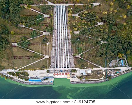 Gateway of Kyiv Pumped-Storage Power Plant. On the its sides there are green trees, power lines. Top view panoramic photo. Horizontal.