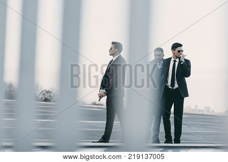 view through fence of businessman with bodyguards standing on helipad