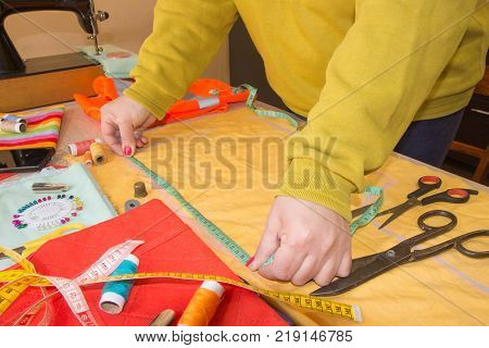 Fashion designer Woman tailor posing at her workplace with cut fabric free space on wooden wall. Garment industry tailoring concept
