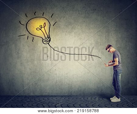 Young man using a laptop with light bulb plugged in it