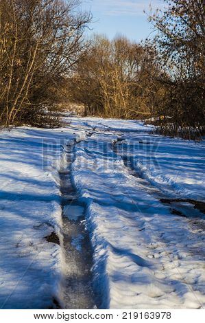 Beautiful spring landscape. Country road near the forest and fields in a sunny spring day.Snowbreak.