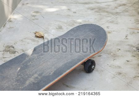 skateboard leaning against white concrete wall and dirty floor