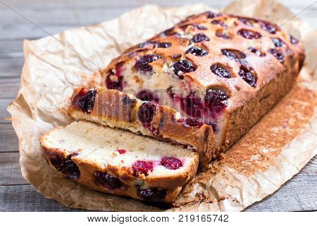 Slices of fresh sponge cake with cherries on a wooden background