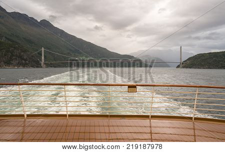 Cruise ship sails under Hardanger bridge near Eidfjord in Norway