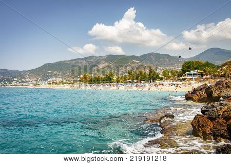 Landscape of resort sea beach in lagoon bay on summer sunny day. Rocky beach and mountains on horizon in tropical sea town. Beautiful paradise nature of Turkey perfect for relax