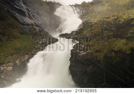 Kjosfossen waterfall flows down valley by the station on the train between Flam and Myrdal in Norway