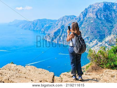 Woman taking photos of beautiful scenery at Path of Gods on Tyrrhenian sea Amalfi coast Italy