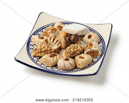 Dish with traditional variety of festive Moroccan cookies on white background
