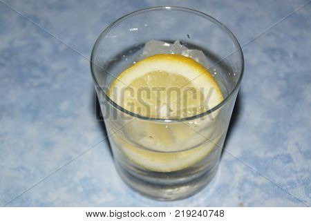 A glass with a slice of lemon and some ice cubes.  The lemon (or yellow lemon) is a citrus fruit, a fruit of the lemon tree, the juice of which has a pH of 2,5. The lemon tree (Citrus silt) is a shrub of 5 10 meters away from high, evergreen, of the famil