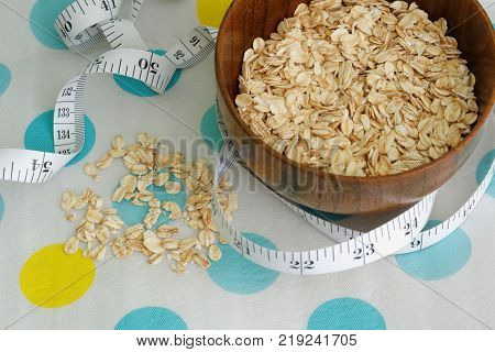 Rolled oats in a wooden bowl with tape measure