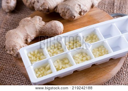 Frozen ginger cubes on a cutting board on a wooden table