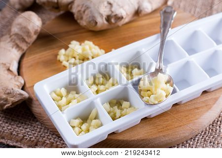 Pieces of ginger in a container for freezing ice cubes on a wooden table