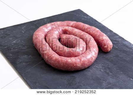 Rolled uncooked botifarra or Catalan sausage. Isolated over black slate