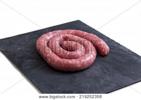 Rolled uncooked botifarra or Catalan sausage. Isolated over black slate