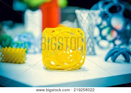 Abstract object of a yellow color printed on a 3d printer on a white table. Fused deposition modeling, FDM. Progressive modern additive technology. Concept of 4.0 industrial revolution