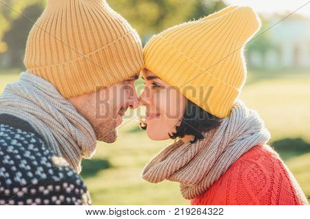 Close up portrait of lovely couple wear warm hats and scarf look with eyes full of happiness and enjoyment going to have sweet kiss enjoy togetherness. People relationship and love concept