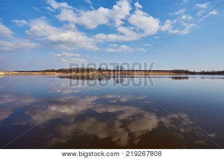 Natural landscape, tree without leaves, river, shore, forest, river grass, reflection many trees blue sky ravines