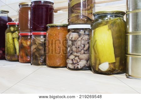 Storage shelves in pantry with homemade canned preserved fruits and vegetables.