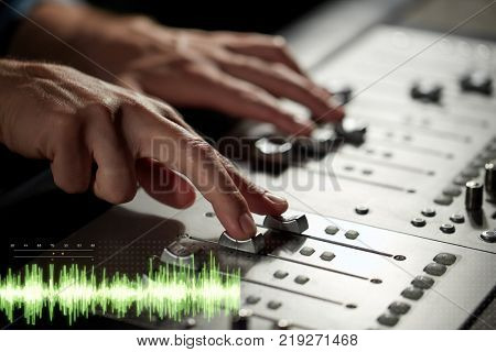 music, technology, people and equipment concept - sound engineer hands using mixing console at recording studio