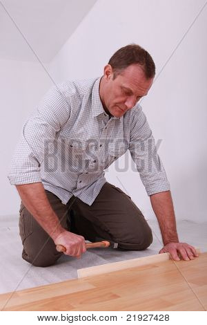 trabalhador manual que fixa um soalho laminado