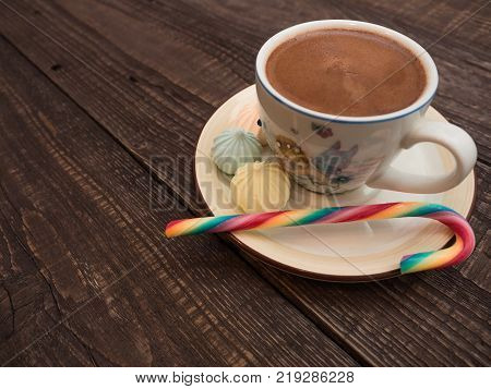 Freshly brewed cocoa and colorful biseza with candy on an old wooden table