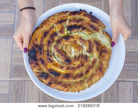 Round burek or pie in white plate, close up, top view. Turkey