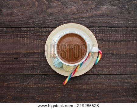 Freshly brewed cocoa and colorful biseza with candy on an old wooden table