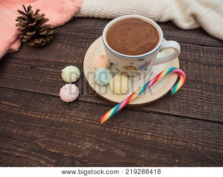 Freshly brewed cocoa and colorful biseza with candy on an old wooden table
