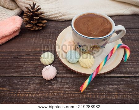 Freshly brewed cocoa and colorful biseza with candy on an old wooden table