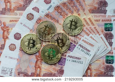 Coins bitcoin, lie on bill of 5000 thousand rubles. The banknotes are spread out on the table in free order. Gold coins are crypto currency.