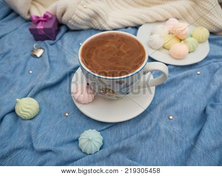 Freshly brewed cocoa with foam and colorful bise on the table