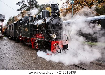 Steam train traveling along the railway line with steam bellowing out the sides and the top
