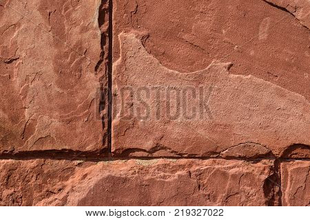 red sand stone texture pattern on surface of the wall. flaking red sandstone rock surface with topographic texture.