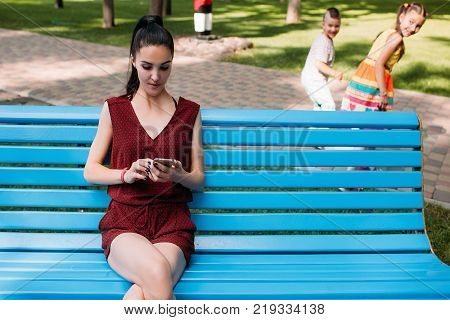 Children secretly escape from mother at park. While the parent is distracted. Reckless careless babysitter deep in social network