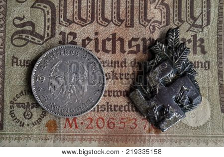 ILLUSTRATIVE EDITORIAL.Polish Army insignia (found with metal detector near Kiev).German vintage banknote WWII time.  .Kiev,Ukraine December 21 ,2017