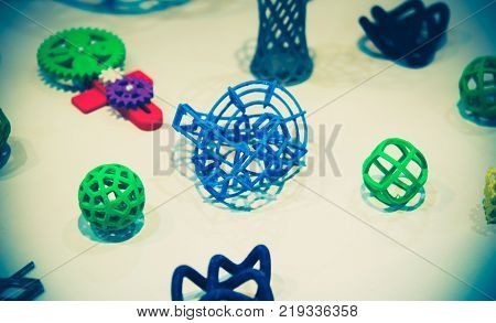 Many abstract models bright colorful objects printed on a 3d printer on a white table. Fused deposition modeling, FDM. Progressive modern additive technology. Concept of 4.0 industrial revolution