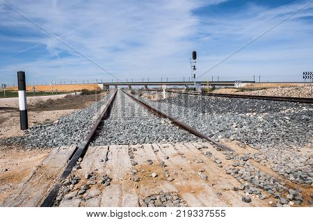Level crossing with no barrier in Toledo Province, Spain. In the background can be seen the Madrid-Levante High-Speed Railway.