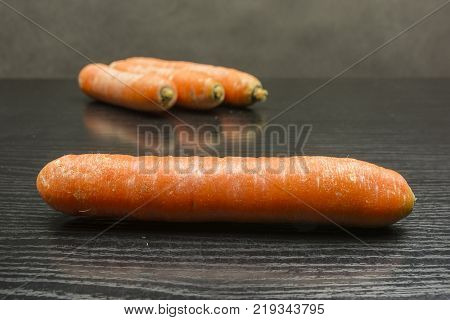 Raw fresh carrot on a wooden table.