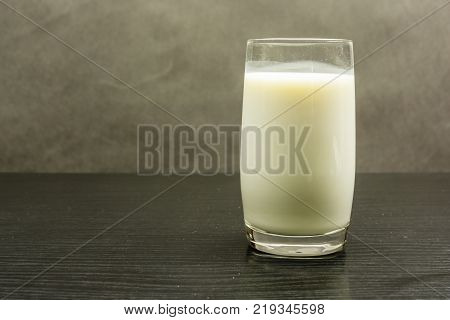A glass of pasteurized cow's milk on a wooden table.