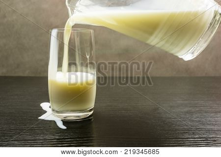 Milk spilled while pouring from a jug into a glass.