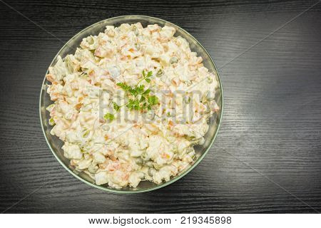 Bowl with vegetable salad prepared for the holiday on a wooden table. View from above.