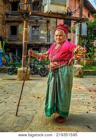 BANDIPUR, NEPAL - OCTOBER 22, 2015 : Very old woman walks with a walking stick in the street of Bandipur