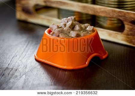 Canned pet food in a orange plastic bowl