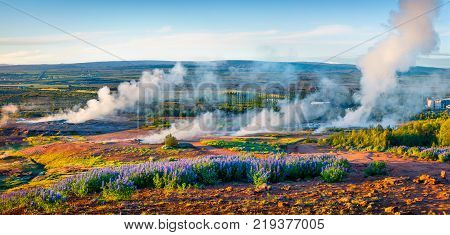 Erupting of the Great Geysir lies in Haukadalur valley on the slopes of Laugarfjall hill. Panorama of foggy summer morning in Southwestern Iceland Europe. Artistic style post processed photo.