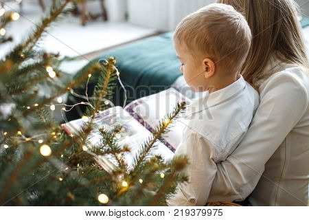 mom and son are reading a book. New Year's fairy tale for the night, raising children.