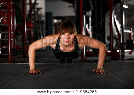 Gorgeous brunette warming up and doing some push ups a the gym.
