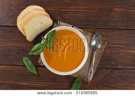 Pumpkin and carrot soup with cream and parsley on dark wooden background Top view