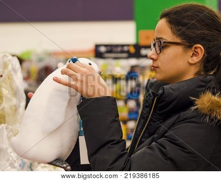 Cheerful girl in glasses with diopters choosing gifts at Christmas fair