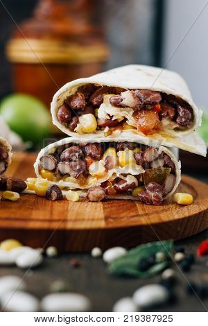 Nice vegetarian burrito over black table on wooden board